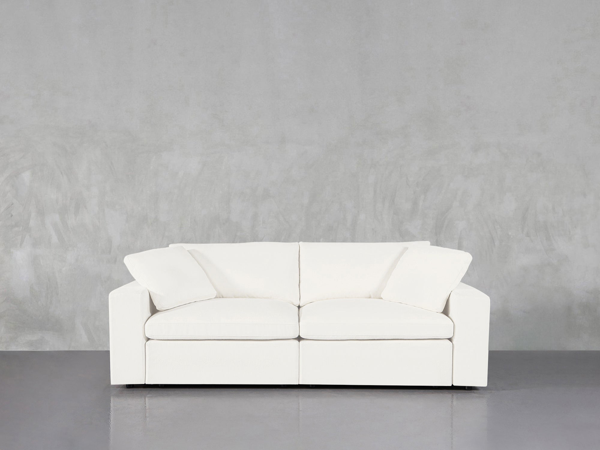 White loveseat against concrete wall