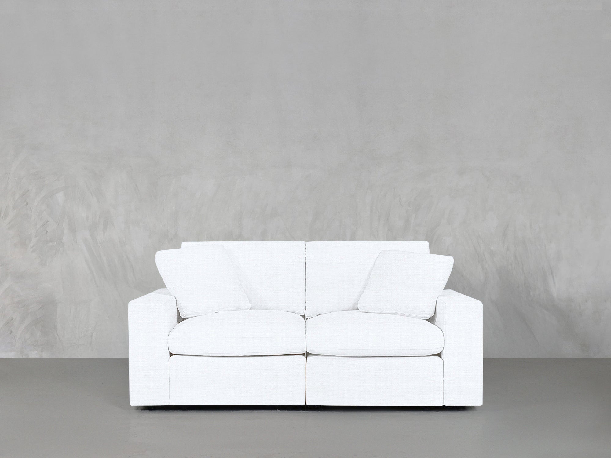 White loveseat against concrete wall