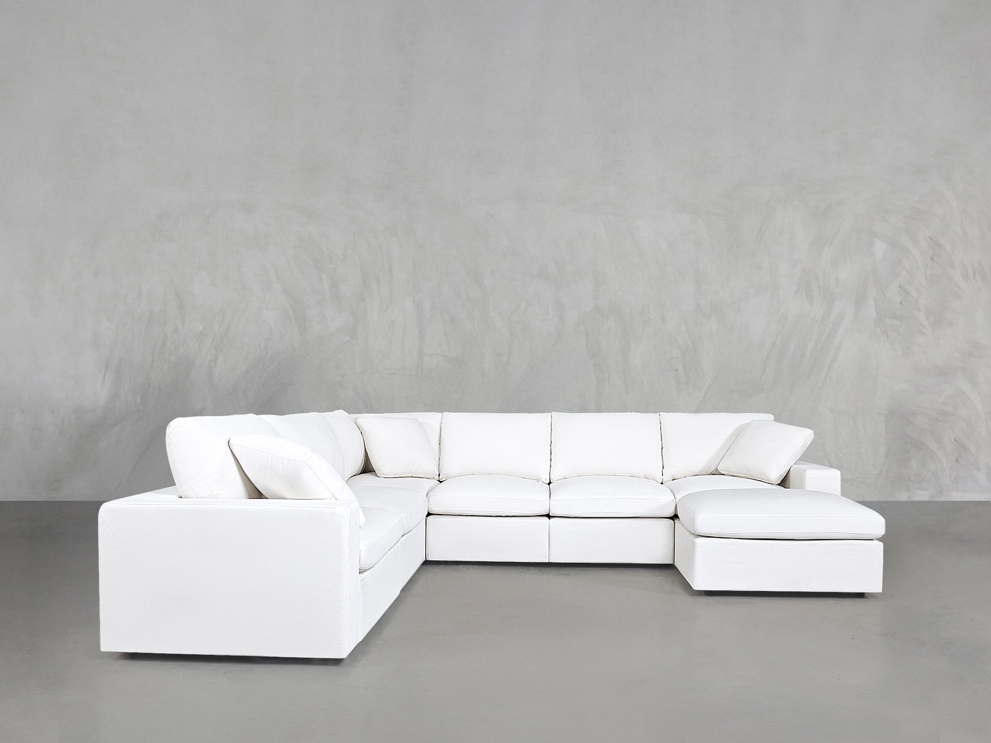 White sectional sofa set against a gray concrete-like wall, straight profile