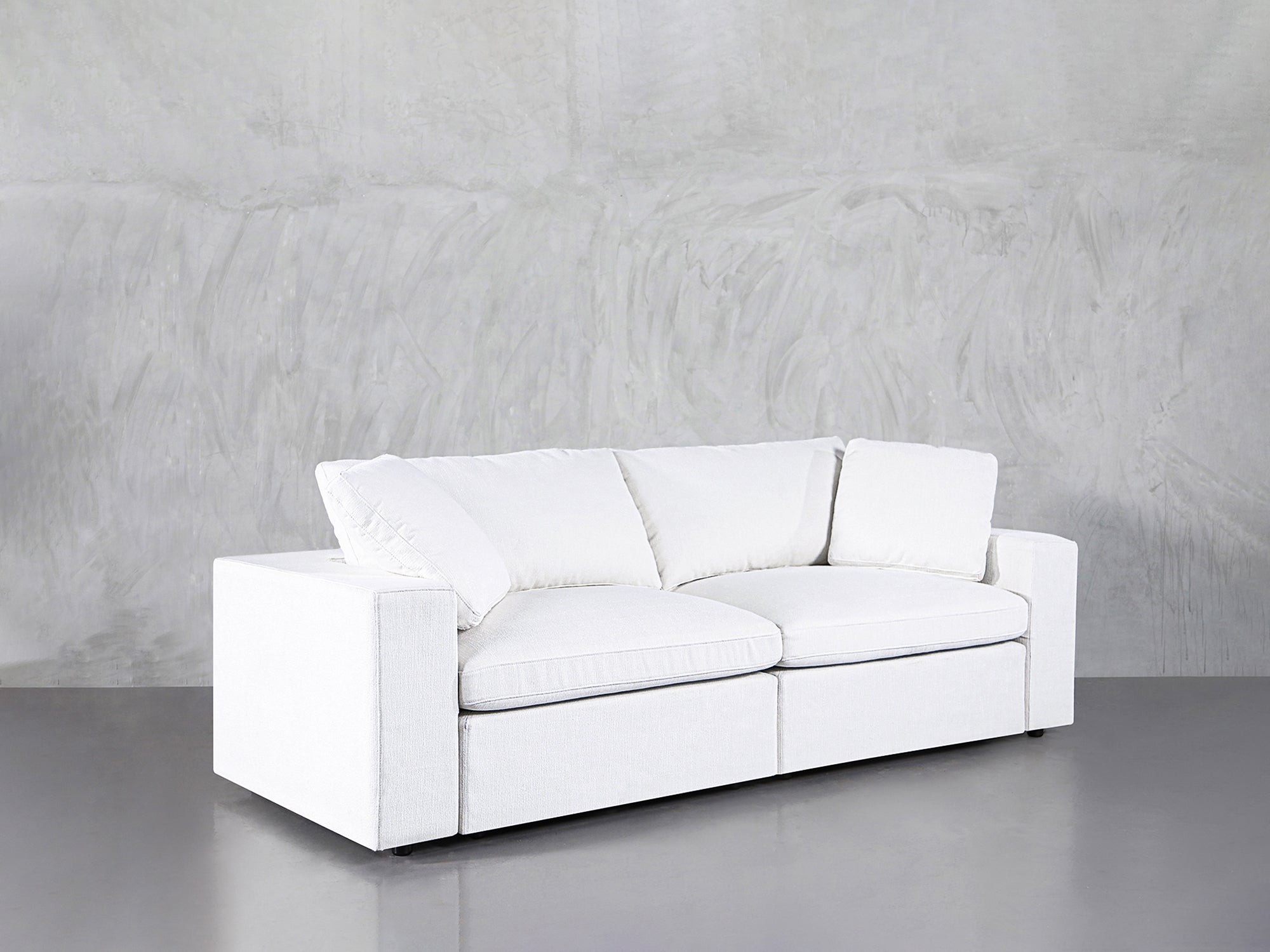 White 2-seat loveseat with pillows on a concrete floor