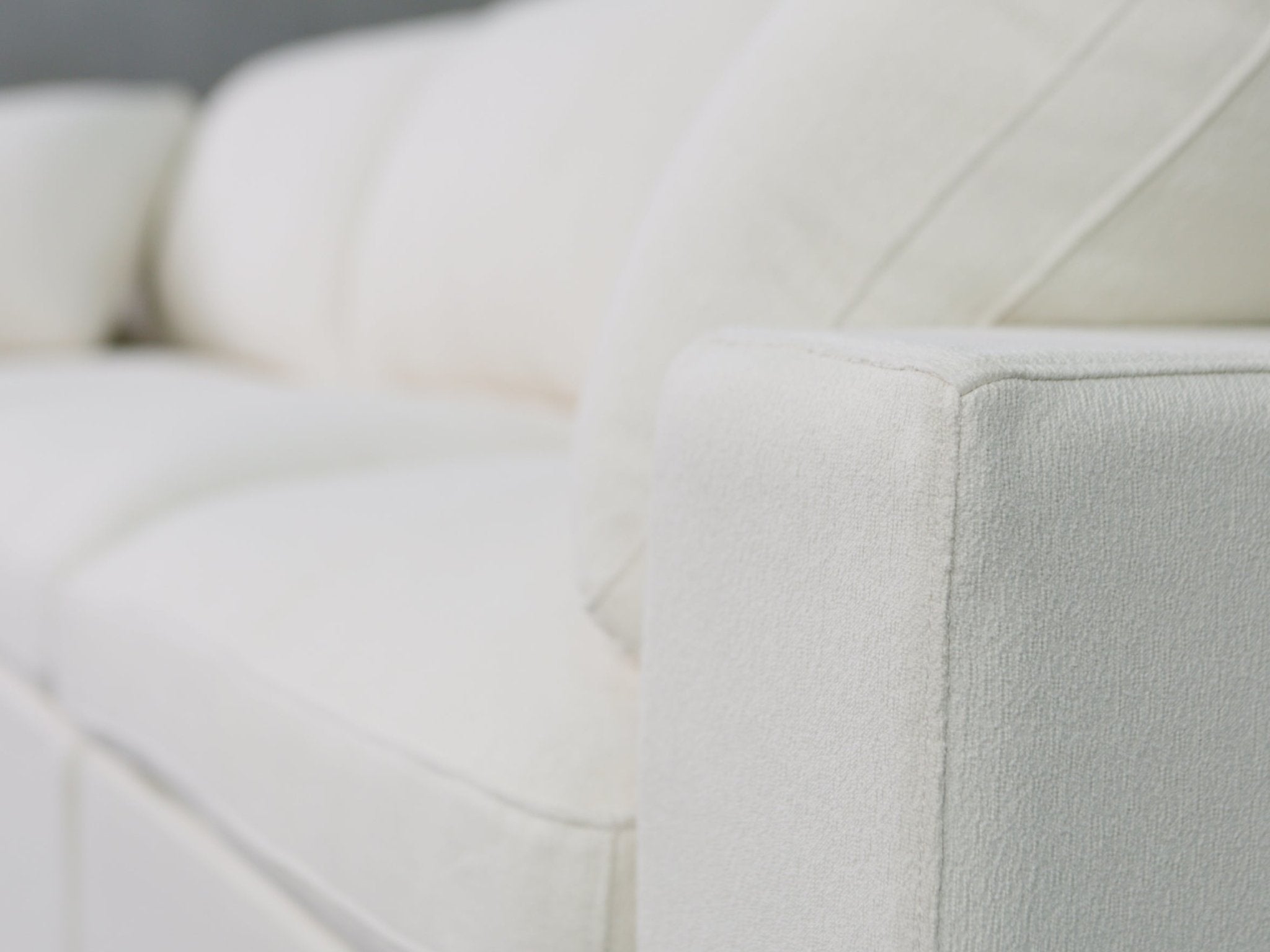 Close-up of white fabric upholstery on arm of sofa
