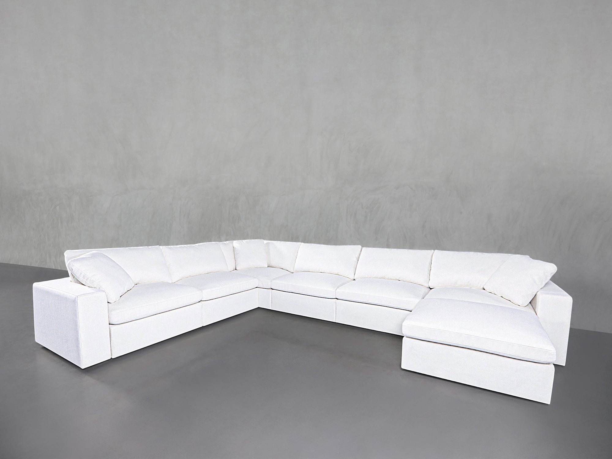 White sectional sofa configured in an L-shape with rounded cushions and back pillows