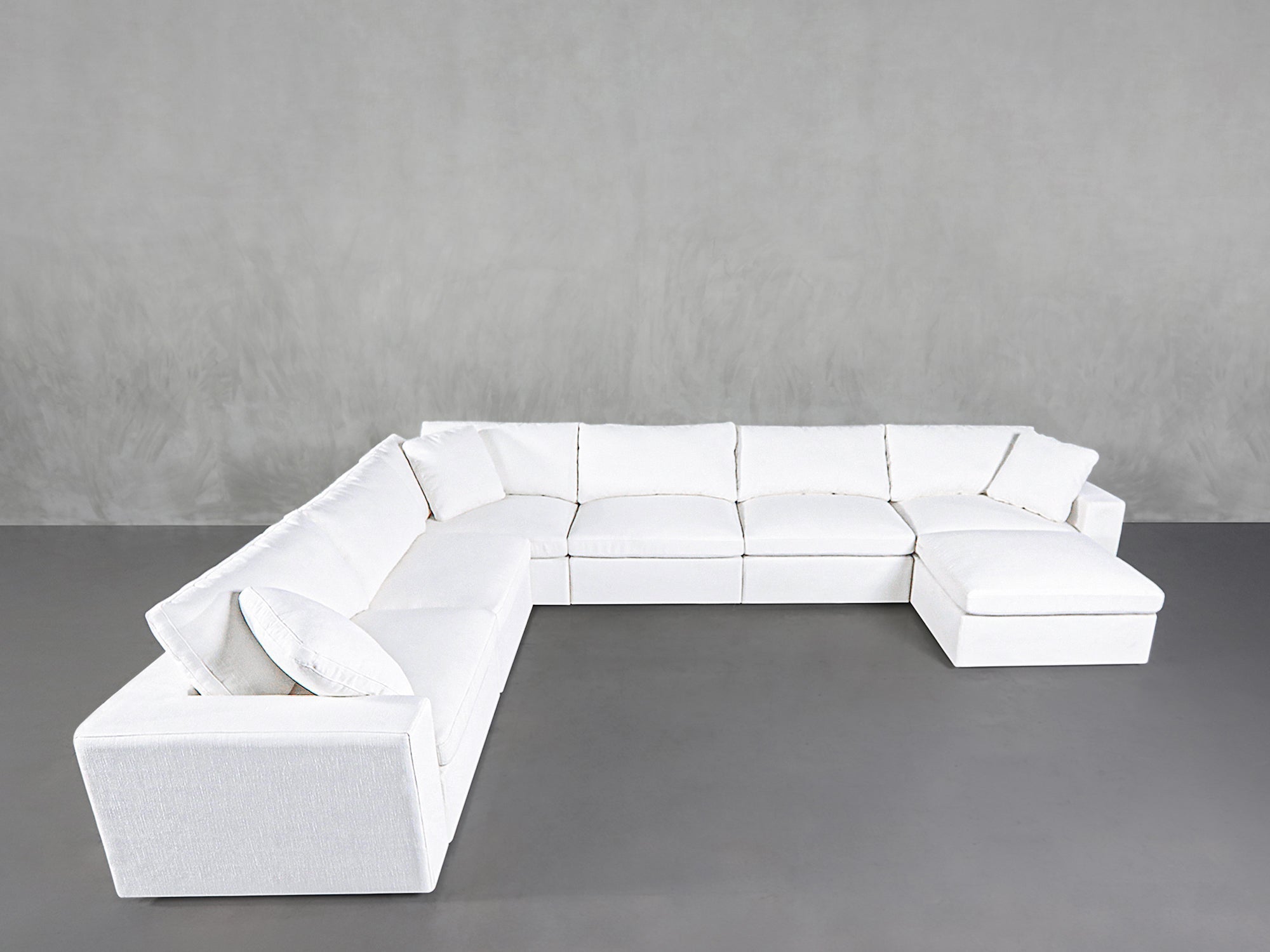 White sectional sofa with matching chaise on left and a large backrest, in a modern space